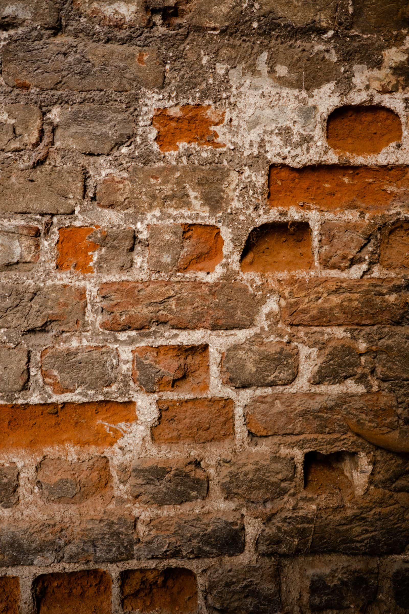 An old brick wall showing eroded mortar between the courses